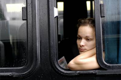 A girl watches as the busy bus terminal bustles with travelers.