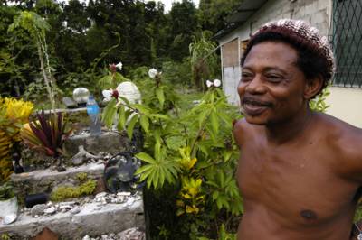 A Rasta proudly displays his collection of found objects and brightly colored plants.