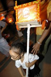 A young child carries a cart-shaped lantern in the Independence Day festivities.