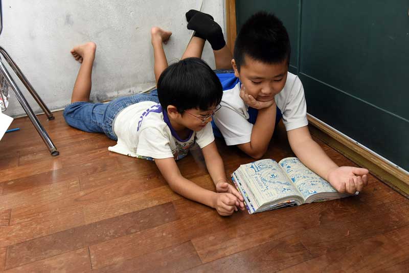 Young boys read together at the Aisei Daycare in Ginowan near Marine Corps Air Station Futenma, Okinawa, Japan where their teacher, Ginko Ueya, 61, is worried about the safety of her young students. In 2004 she walked past the wreckage of a crashed military helicopter near her home. Every day she worries about another crash hitting schools and daycares near the base, she says. (Tiffany Tompkins-Condie, McClatchy.)