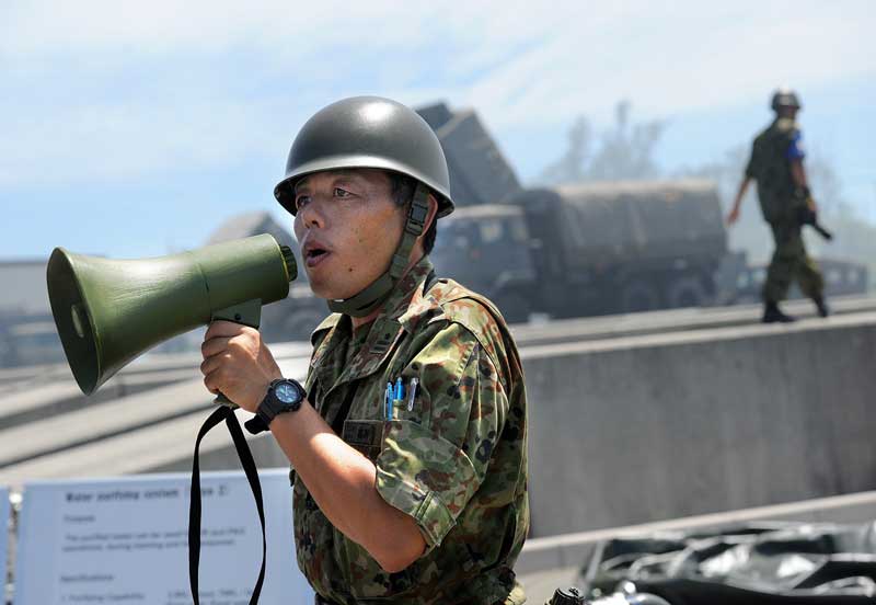 A Japanese soldier explains a water filtration center during a joint exercise between the U.S. Marines and the Japanese Ground Self-Defense Force in Okinawa, on July 23, 2015. Growing defense spending will enable the construction of a headquarters for a new Japanese Air Self-Defense Force squadron. (Tiffany Tompkins-Condie, McClatchy.)