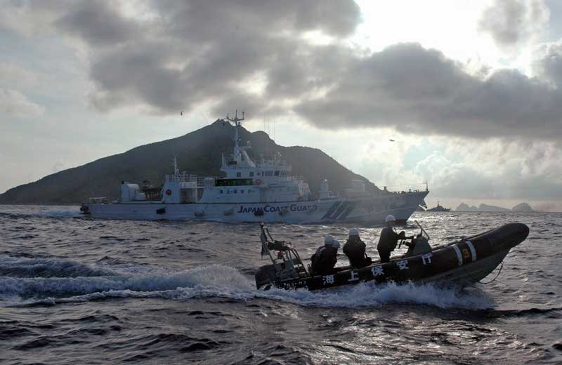 A Japanese Coast Guard boat and vessel sail alongside a Japanese activists' fishing boat (not in photo), warning the activists away from a group of disputed islands — called Diaoyu by China and Senkaku by Japan — on Aug. 18, 2013. (Emily Wang, AP.)
