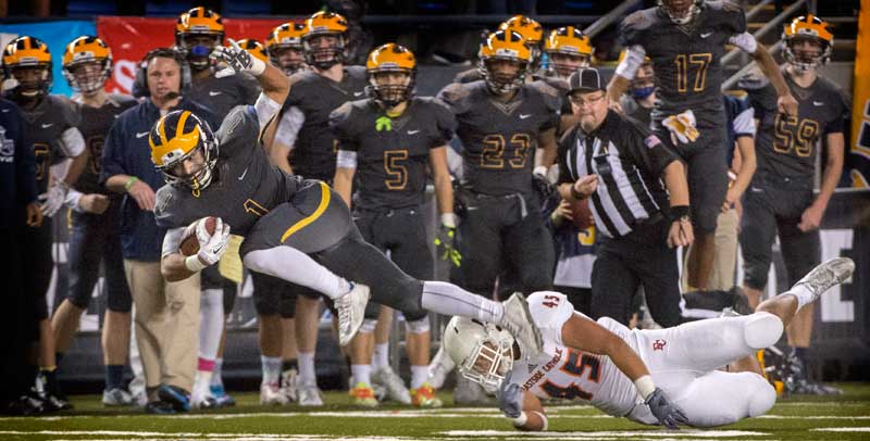 Bellevue’s Isaiah Gilchrist, left, flies to a first down during 3A championship game in 2015. (Lui Kit Wong, staff file.)