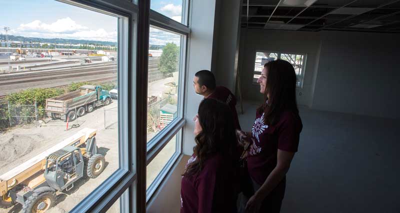 Summit Olympus High School principal Gina Wickstead, right, with her staff look out of a classroom window last week at construction outside of Summit Olympus High School in Tacoma. (Lui Kit Wong, staff photographer.)